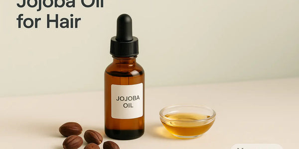 A Keyoma bottle of jojoba oil with a dropper stands next to a small bowl of oil and several jojoba nuts on a light-colored surface.