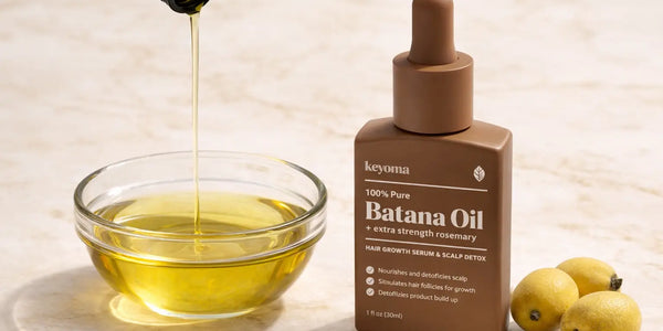 Closeup of Keyoma Batana Oil pouring into glass bowl on marble countertop.