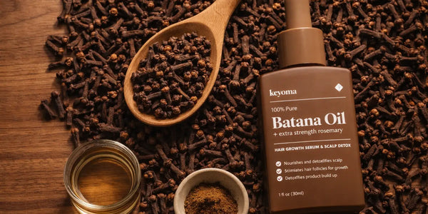 Keyoma Batana Oil flatlay surrounded by whole cloves and oil jar for scalp treatment.