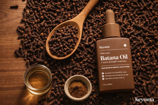 Keyoma Batana Oil flatlay surrounded by whole cloves and oil jar for scalp treatment.
