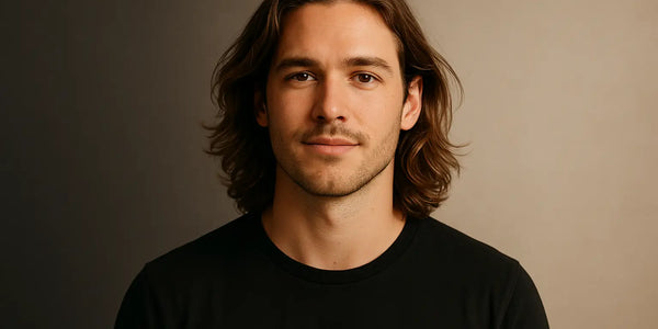 Portrait of long-haired man in black tee against warm studio gradient; Keyoma highlights healthy shine, grooming.