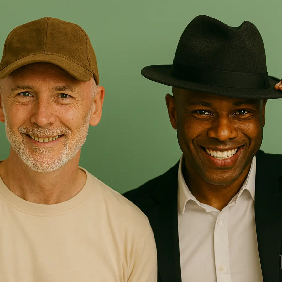 A Keyoma illustration showing a confident bald man in a casual shirt wearing a baseball cap and standing beside a smiling man in a blazer holding a fedora