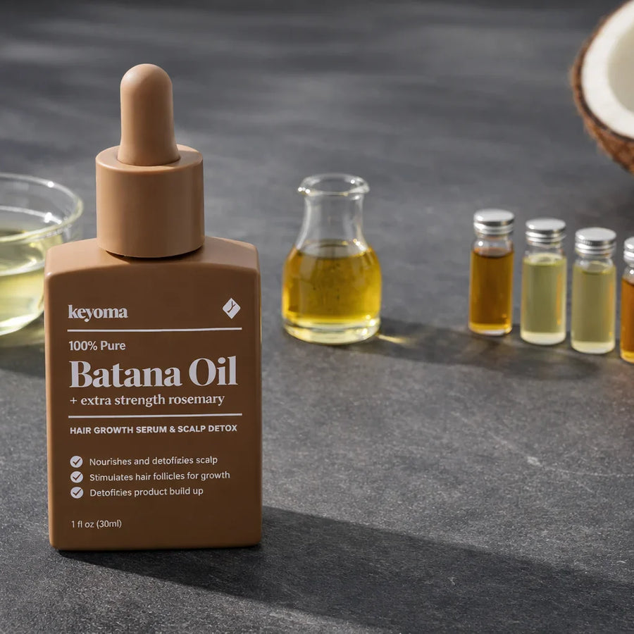 Keyoma batana oil with rosemary serum bottle displayed with natural oils and ingredients.