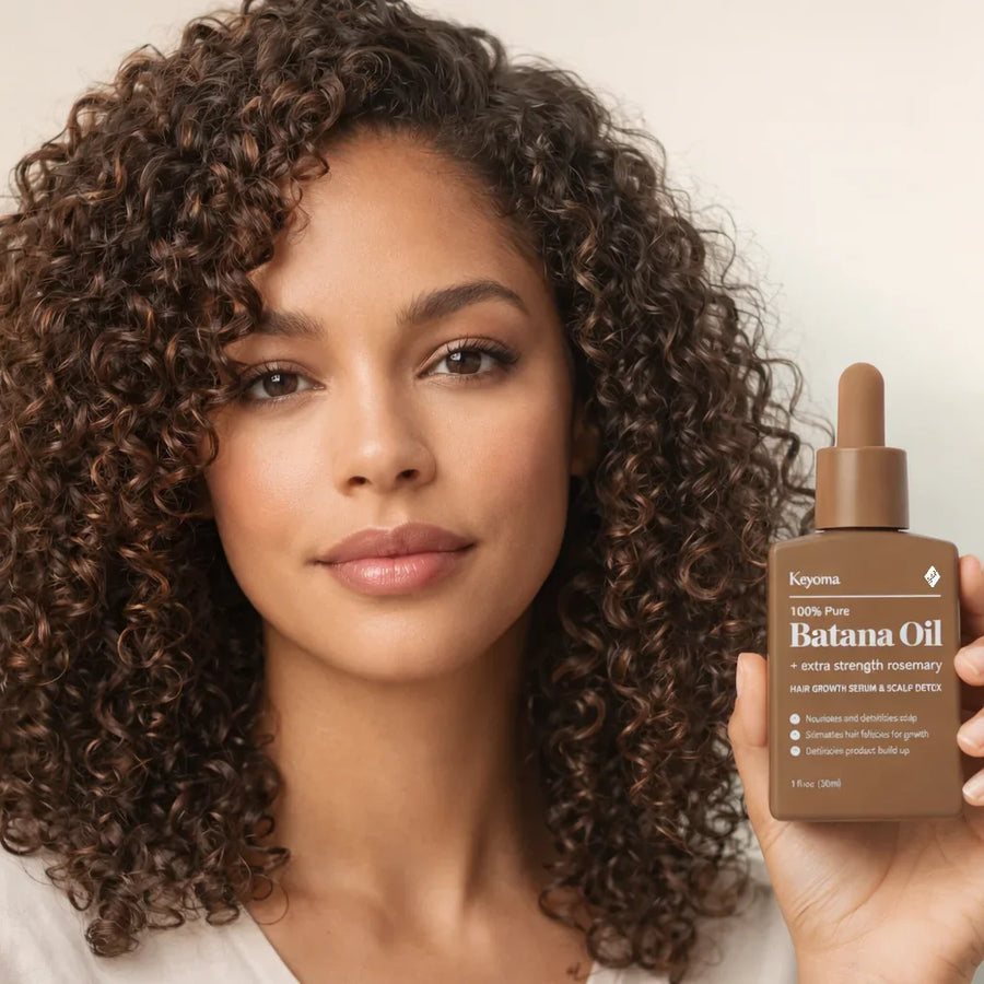 Model with defined curls holds Keyoma batana oil, highlighting natural curl definition and healthy hair shine.